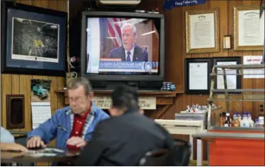  ?? DAVID GOLDMAN — ASSOCIATED PRESS ?? A newscast showing President Donald Trump plays on an old television set as customers play cards in the Frosty Freeze restaurant in Sandy Hook, Ky., earlier this month.