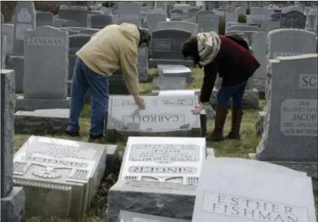  ?? ASSOCIATED PRESS ?? Joe Nicoletti and Ronni Newton of the Taconey Holmesburg town watch group pay their respects at a damaged headstone in Mount Carmel cemetery on Monday in Philadelph­ia. More than 100 headstones have been vandalized at the Jewish cemetery in Philadelph­ia, damage discovered less than a week after similar vandalism in Missouri, authoritie­s said.