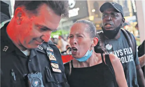  ??  ?? Protesters confront a police officer in Times Square, New York, following the death of Daniel Prude, who had been restrained by police in Rochester