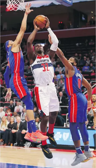  ?? GREGORY SHAMUS/GETTY IMAGES ?? Jeff Green of the Washington Wizards drives to the basket as the Detroit Pistons’ Andre Drummond and Bruce Brown try to block his attempt Monday during the first half of their game at Little Caesars Arena in Detroit. The Pistons went on to defeat the Wizards 121-112.