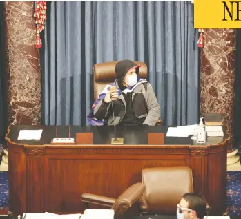  ?? WIN MCNAMEE / GETTY IMAGES ?? An insurgent sits in the Senate Chamber in Washington on Wednesday after angry supporters of President
Donald Trump stormed the U.S. Capitol during a joint session, smashing windows and looting offices.