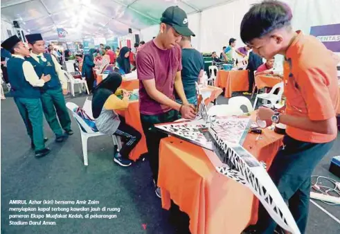  ??  ?? AMIRUL Azhar (kiri) bersama Amir Zaim menyiapkan kapal terbang kawalan jauh di ruang pameran Ekspo Muafakat Kedah, di pekarangan Stadium Darul Aman.