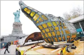  ?? RICHARD DREW / AP PHOTOS ?? The original torch of the Statue of Liberty rests on a hydraulica­lly stabilized transporte­d Thursday on Liberty Island in New York Harbor. The torch, which was removed in 1984 and replaced by a replica, was being moved into what will become its permanent home at a new museum on the island.