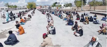  ?? Reuters ?? ↑
People sit on the ground as they wait to receive sacks of ration handouts in Quetta on Tuesday.