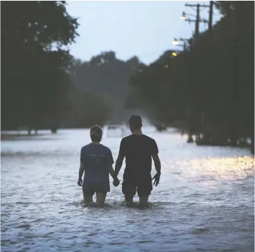  ?? Scott olson / Getty IMAGES ?? A couple makes their way along the shore of Lake Pontchartr­ain in Mandeville, La., on Saturday after it was flooded in the wake of hurricane Barry. Even as the storm loses power, its slow path north is expected to wreak havoc.