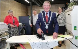  ??  ?? Cllr Doyle helping iron a few things out during a visit to the community laundry at IRD Duhallow in Newmarket.