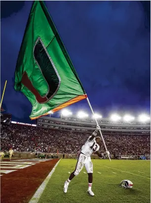  ?? BUTCH DILL / GETTY IMAGES ?? DeeJay Dallas flies the flag during Miami’s celebratio­n following last weekend’s victory at Doak Campbell Stadium, which ended a seven-year drought against Florida State.