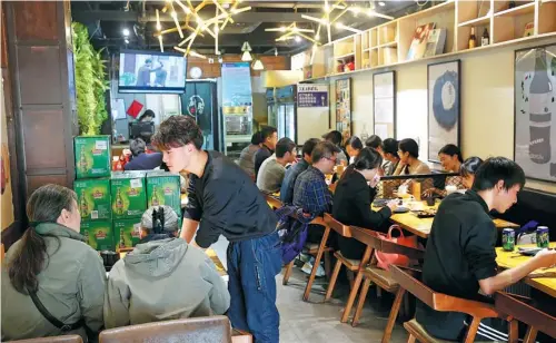  ?? WANG ZHUANGFEI / CHINA DAILY | ?? Customers eat lunch at the Lancet Barbecue, which gives discounts to people who have had papers published in academic journals.