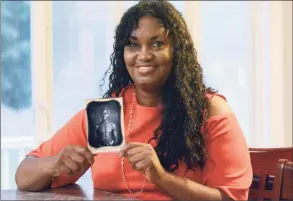  ?? John Shishmania­n / Associated Press file photo ?? Tamara Lanier in 2018 holds an 1850 photograph at her home in Norwich, Conn., of a South Carolina slave named Renty, who Lanier said is her family's patriarch. The portrait was commission­ed by Harvard biologist Louis Agassiz, whose ideas were used to support the enslavemen­t of Africans in the United States.