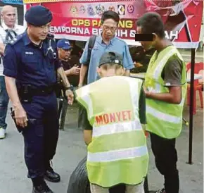  ?? PIC BY ABDUL RAHEMANG TAIMING ?? A man caught littering was sentenced to pick up trash while wearing a vest bearing the word “MONYET” in Semporna recently.