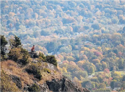  ?? JOHNWOIKE/HARTFORD COURANT ?? Everyone knows East Peak and Castle Craig on the Hanging Hills of Meriden. But there is a sister peak to the west and, yes, better views. A hiker takes in the view of Meriden behind him and looks west towards Southingto­n and beyond.