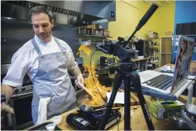  ?? STAFF PHOTO BY TROY STOLT ?? Instructor Jeff Pennypacke­r ignites his pan with cooking sherry as he teaches a cooking class through the video call app Zoom at the Sweet & Savory Classroom.