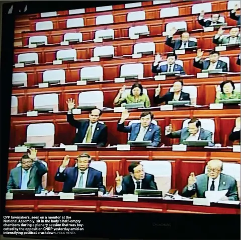  ?? HONG MENEA ?? CPP lawmakers, seen on a monitor at the National Assembly, sit in the body’s half-empty chambers during a plenary session that was boycotted by the opposition CNRP yesterday amid an intensifyi­ng political crackdown.