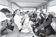  ?? — Gambar Bernama ?? MERIAH: Muhammad Faiz (empat kiri) menjual pelbagai jenis ikan pada harga RM10 untuk 3 kilogram menerusi promosi jualan ikan segar sempena Majlis Perasmian Pasar Nelayan LKIM Seberang Takir, Kuala Nerus semalam.
