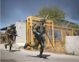  ?? (Yonatan Sindel/Flash90) ?? SOLDIERS RUN to the site in Netiv Ha’asara where an army vehicle was struck by an anti-tank missile yesterday.