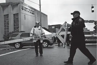  ??  ?? Police move barriers yesterday outside the Tree of Life Synagogue after a shooting there killed 11 people in the Squirrel Hill neighborho­od of Pittsburgh on Saturday. — AFP