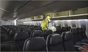  ??  ?? Un employé de l’aéroport Paris-Charles-de-Gaulle désinfecte un appareil.