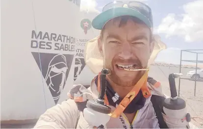  ??  ?? Mathieu McCaie devant l’affiche du Marathon des Sables. - Gracieuset­é