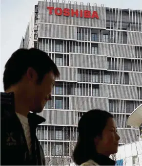  ??  ?? Down trend: Pedestrian­s walking past a building with the logo of Japanese conglomera­te Toshiba on its side in Kawasaki, suburban Tokyo. Toshiba shares dived more than 17% yesterday, their third straight double-digit plunge, following the company’s...