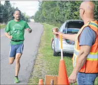  ?? ERIC MCCARTHY/JOURNAL PIONEER ?? Overall winner Mike MacKinnon reaches for some water at the half-way point of the run leg in Saturday’s eighth annual Mill River Sprint Triathlon.