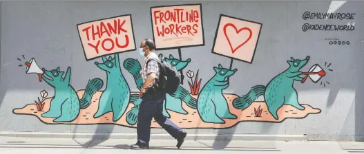  ?? PETER J. THOMPSON ?? A pedestrian wearing a mask walks past a mural supporting frontline workers on Toronto’s Yonge Street during the COVID-19 pandemic earlier this week. Almost every sector of the Canadian economy has been hit hard by the shutdown, with those relying on consumer spending suffering the most.
