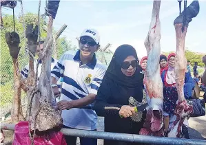  ??  ?? ZAHIRUDDIN (kiri) dan Jainab (kanan) turut berkesempa­tan bersama-sama melapah daging korban pada majlis itu.