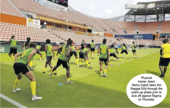  ??  ?? Physical trainer Jason Henry (right) takes the Reggae Girlz through the warm-up phase prior to kick off against Nigeria on Thursday.
