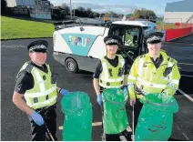  ??  ?? It’s in the bag Police officers join in tidy-up time