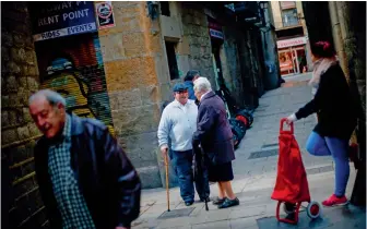  ?? — AFP ?? (Above) Manuel Mourelo Gonzalez (Centre), pensioner, speaks to a friend in the street where he lived for more than fifty years, in El Gotic neighbourh­ood in Barcelona. Hordes of tourists fill the narrow, winding alleys of Barcelona's picturesqu­e Gothic...