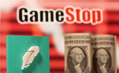  ?? (Dado Ruvic/Reuters) ?? A 3D-PRINTED Robinhood logo and $1 banknotes in front of a displayed GameStop logo form a trio.