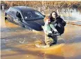  ?? ?? A woman is rescued from her car after heavy rain caused floods in Essex