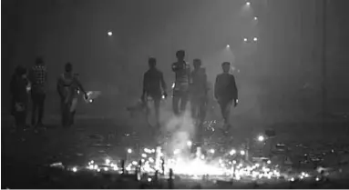  ??  ?? Indian men walk past fireworks amid smog on Diwali. (Photo: EPA)