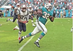  ??  ?? The Dolphins’ Kenyan Drake runs after a lateral to score the game-winning touchdown on the final play against the Patriots on Sunday.