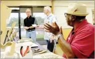  ?? Lynn Atkins/The Weekly Vista ?? Wood Carvers Club President John Brach (center) accepts a donation from the vice president of the Bella Vista Foundation Board Charlie Teal (left) while club member Wilson Scott (right) applauds. The donation will go toward the expenses of the annual...