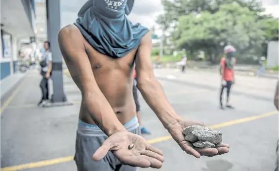  ?? AFP ?? Comparació­n. Un manifestan­te muestra una bala de plomo lanzada por la policía y las piedras con las que los militantes atacan.
