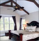  ??  ?? Left: A jetted tub and a rock wall that houses a gas-log  replace form the focal point of the luxurious master bath. Right: The carpeted master bedroom features a vaulted wood-beamed ceiling.