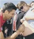  ??  ?? 0 Djokovic signs a pregnant fan’s stomach on the beach