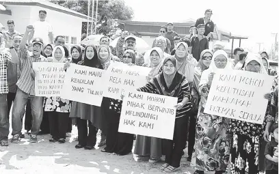  ??  ?? PERTAHAN HAK: Penduduk kampung menterjema­hkan rayuan mereka di atas kad manila.