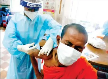  ?? HENG CHIVOAN ?? A monk receives the Sinovac vaccine at Wat Mohamantre­y Primary School in Olympic commune of Phnom Penh’s Boeung Keng Kang district in May.