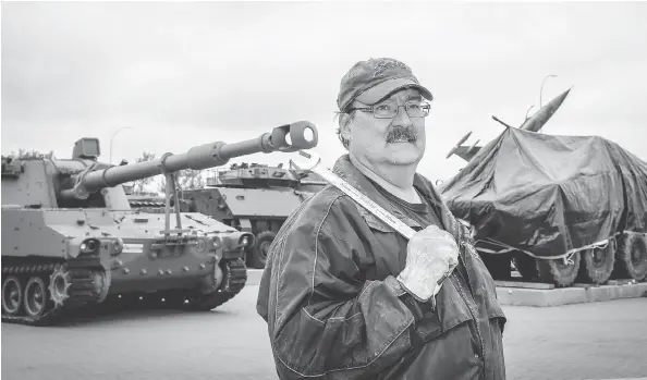  ?? AL CHAREST / POSTMEDIA NEWS ?? Volunteer Brian Mcgregor prepares to work on the Calgary Military Museum’s newest addition, a light armoured vehicle called the LAV III, covered in a tarp at right.