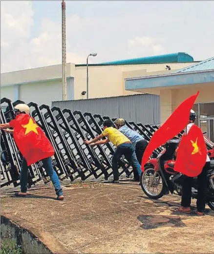  ?? AFP ?? Vietnamita­s envueltos en su bandera tratan de irrumpir en una empresa de Biên Hòa