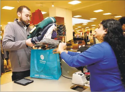  ?? GARY REYES —STAFF ?? An employee checks out a shopper’s items at Macy’s at Westfield Oakridge mall in San Jose before Christmas.