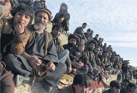  ??  ?? ON THE EDGE OF THEIR SEATS: Afghan spectators watching horsemen compete in the traditiona­l sport of buzkashi on the outskirts of Kabul.