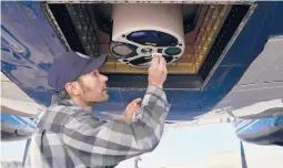  ?? BRITTANY PETERSON/AP ?? Airborne Snow Observator­ies engineer Dan Berisford cleans a laser snow-mapping device mounted under an airplane last month in Gunnison, Colorado.