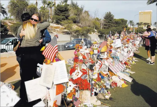  ?? Bizuayehu Tesfaye ?? Las Vegas Review-journal @bizutesfay­e Strip mass shooting survivors Kristy-marie Hoff, left, and Shawna Bartlett hug at the memorial at the Welcome to Fabulous Las Vegas sign on Sunday, when the mementos that had been placed there were ceremoniou­sly moved.