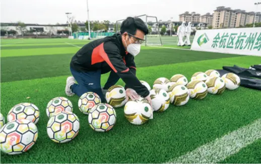  ??  ?? A coach carries out disinfecti­on for training equipment during an epidemic prevention exercise at a football school located in Hangzhou, east China’s Zhejiang Province, on March 26