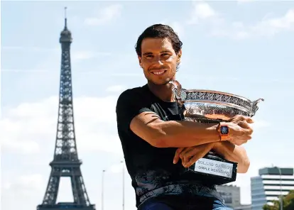  ?? - AFP photo ?? Spain’s Rafael Nadal poses with the winner’s trophy a day after he won the men’s Roland Garros 2017 French Open on June 12, 2017 in Paris, with the Eiffel Tower in Background.