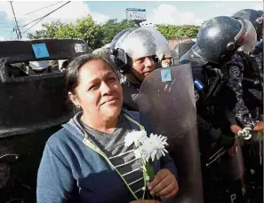  ??  ?? Peaceful gesture: Soldiers standing guard as a supporter of Nasralla holds flowers during a protest. — Reuters