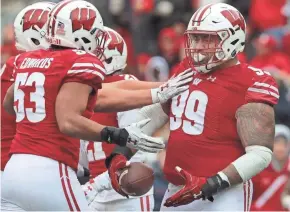  ?? MARK HOFFMAN/MILWAUKEE JOURNAL SENTINEL ?? Wisconsin defensive tackle Olive Sagapolu is congratula­ted by teammates after intercepti­ng a pass against Illinois.