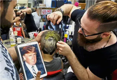  ??  ?? Hair Style One: Omar shaping an image of US President Donald Trump on the back of a customer’s head at his barber shop in Bourj al-Barajneh. — AP